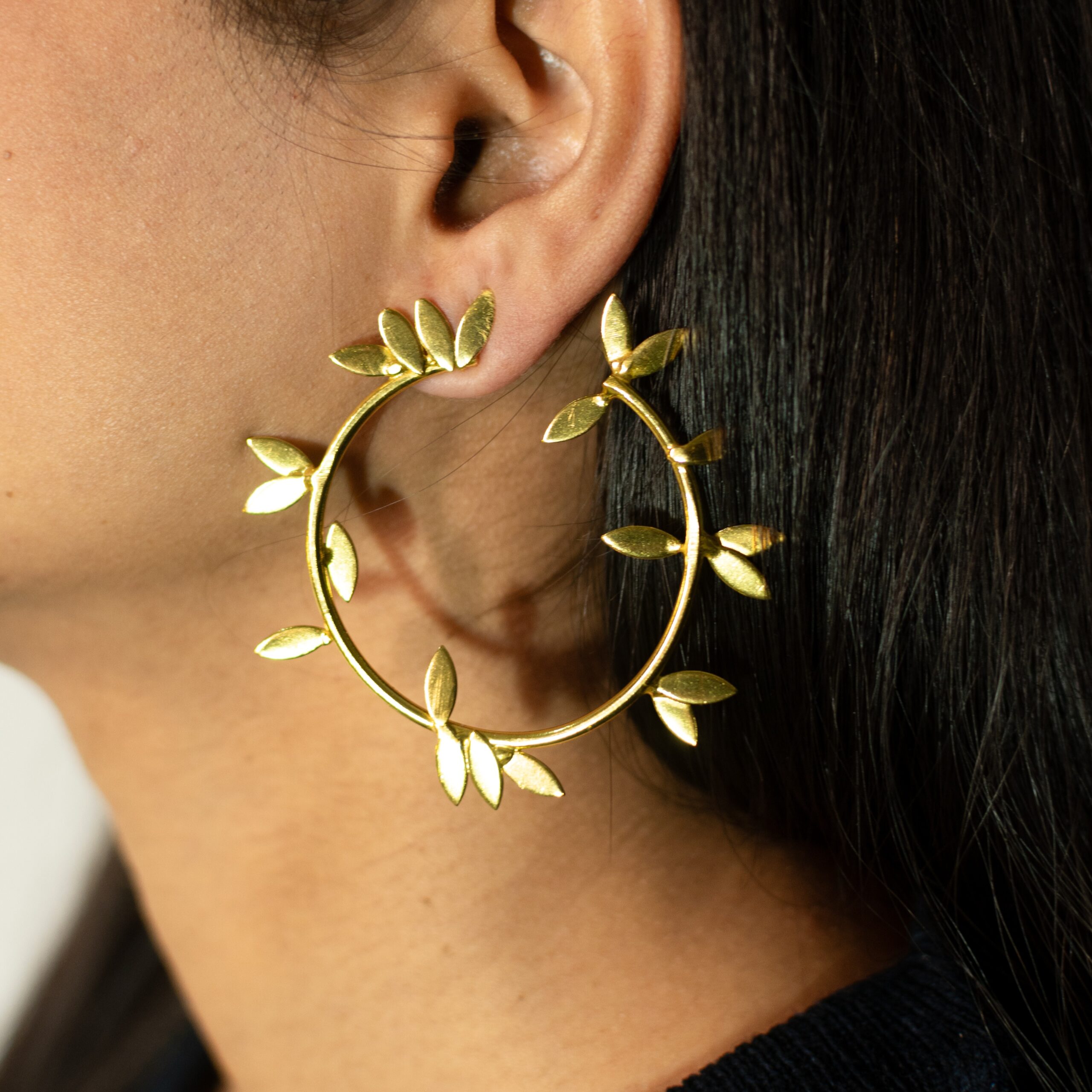 Masaira Laurel gold-plated leaf hoop earring — on-ear three-quarter close-up
