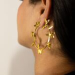 Rear three-quarter view: model wearing Masaira Laurel gold-plated laurel-leaf hoop earring