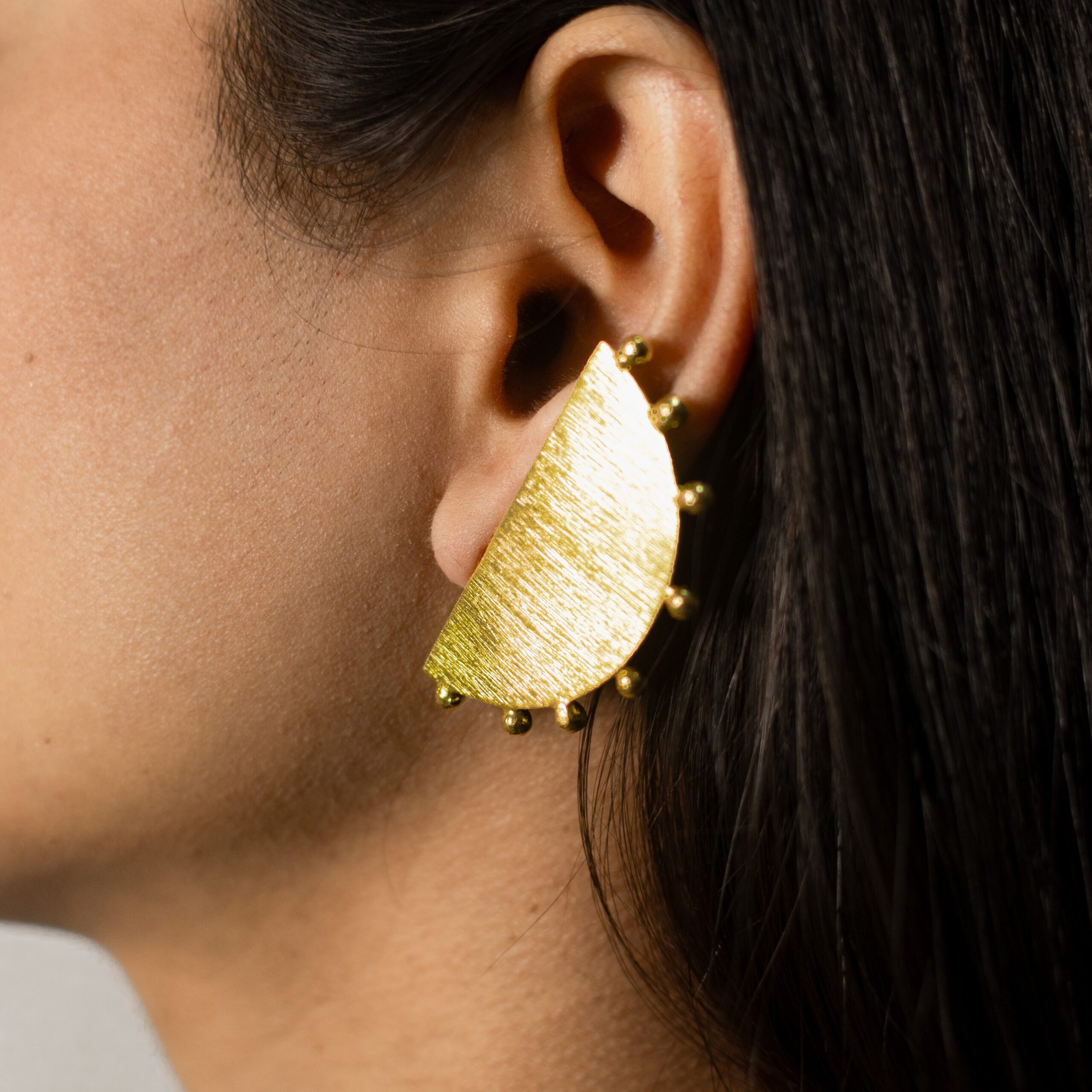 Masaira Eclipse Gold-Plated Half-Moon Beaded Edge Stud Earrings — Close-Up Close-up: Masaira Eclipse brushed gold-plated half-moon stud earring with beaded edge on ear Title