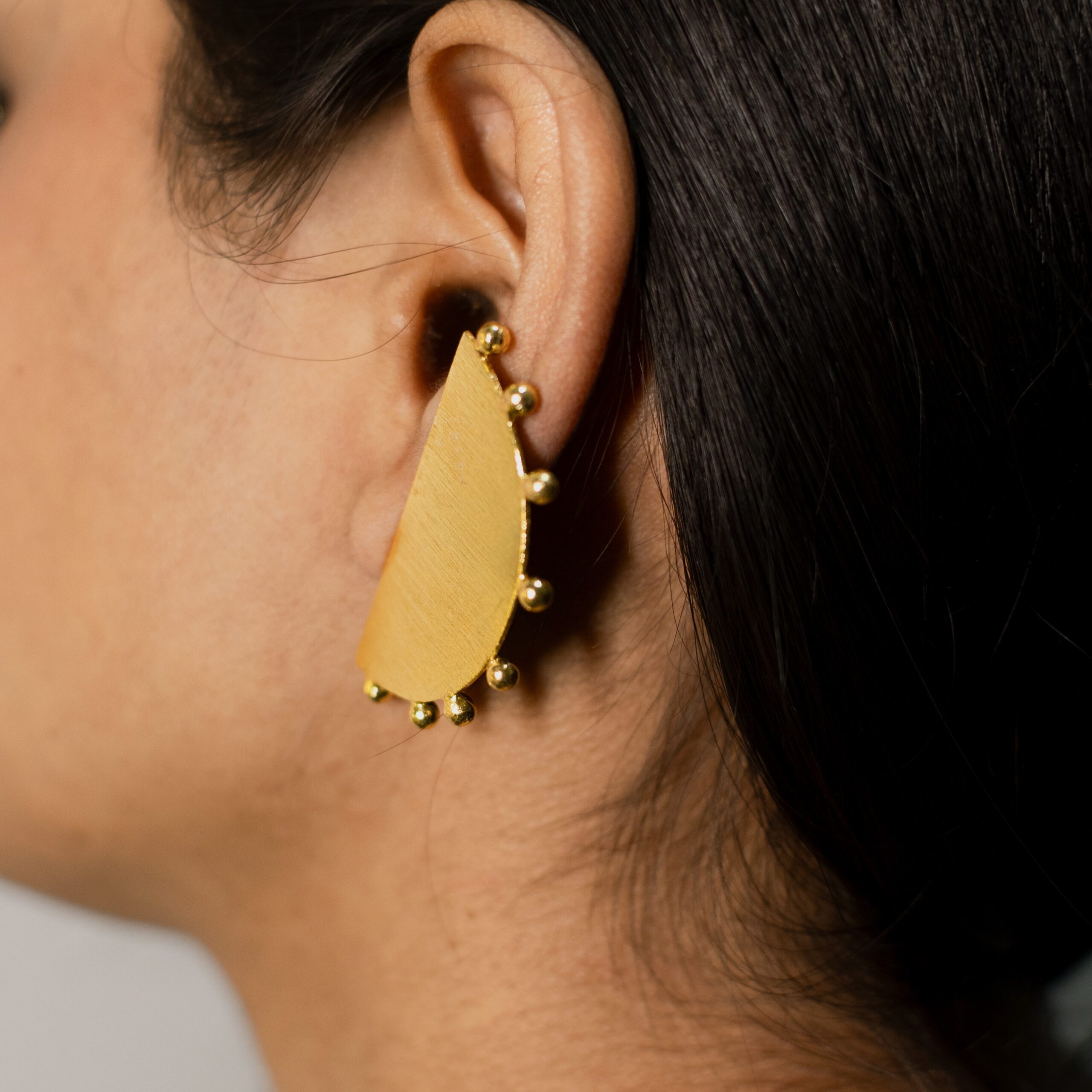 Masaira Eclipse Gold-Plated Half-Moon Beaded Edge Stud Earrings — Left Close Crop Close crop left side: Masaira Eclipse half-moon brushed stud with pronounced beaded edge