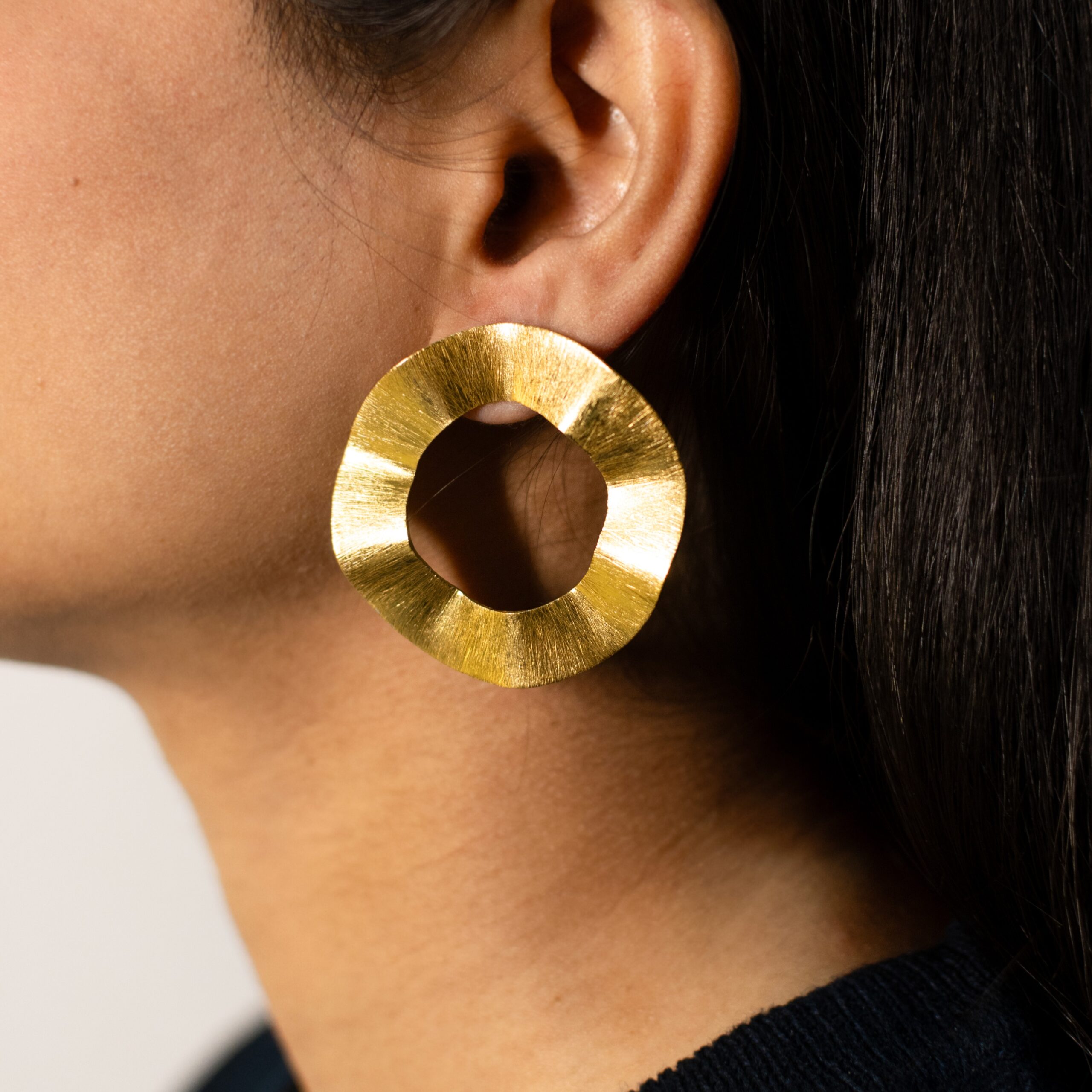 Close-up left side: Masaira Ripple Halo brushed gold-plated wavy ring stud earring