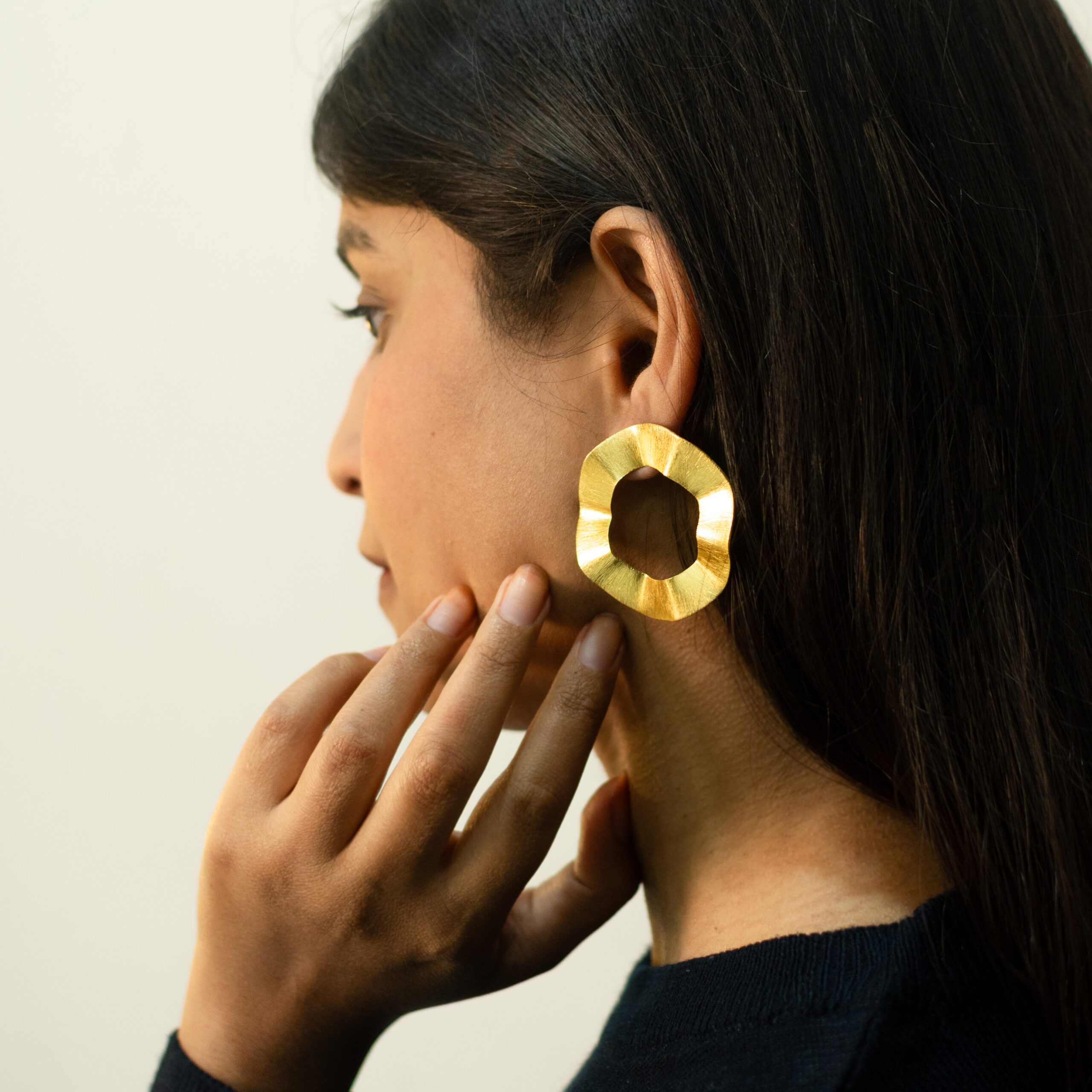 Front-leaning close-up: Masaira Ripple Halo brushed gold-plated wavy open-circle stud