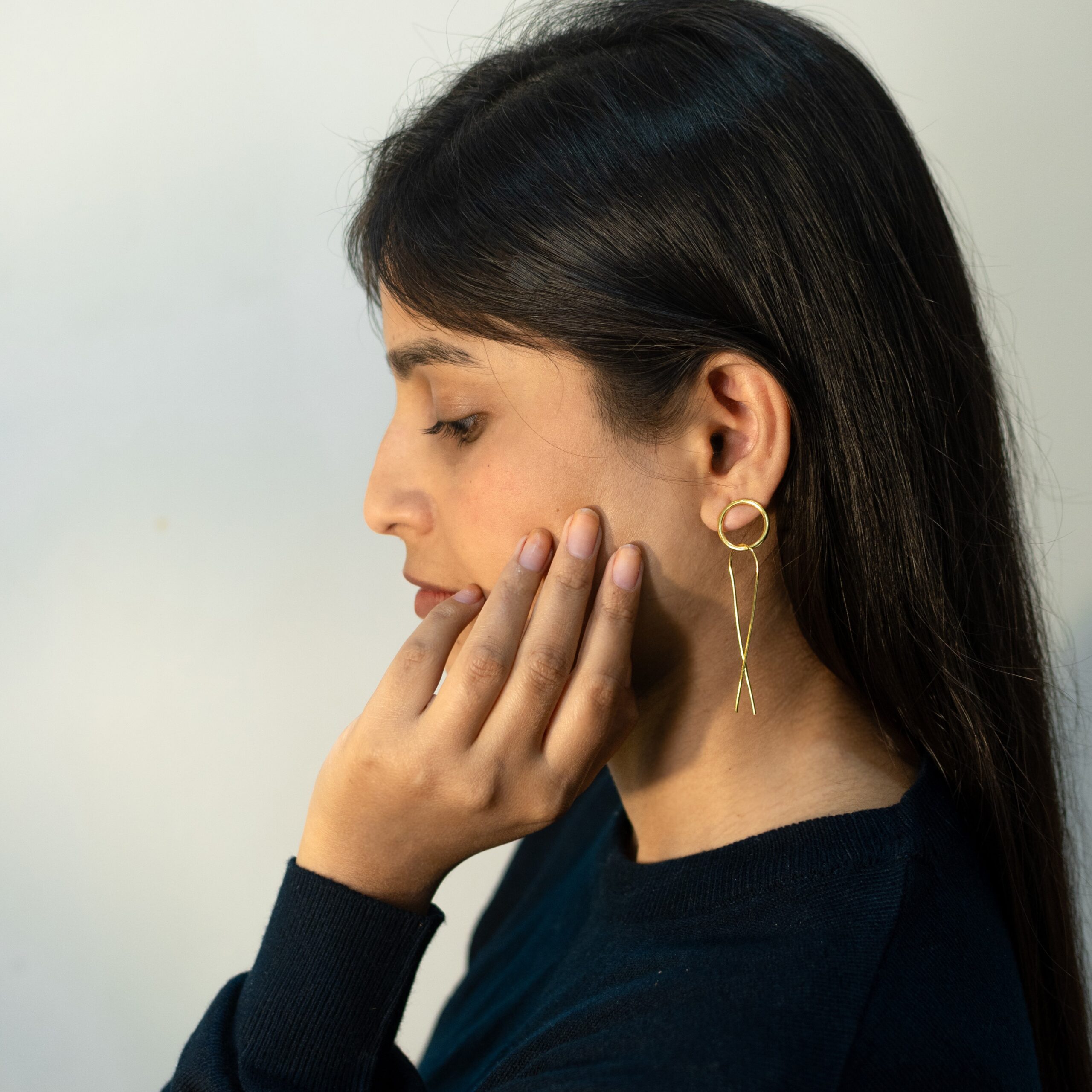 Minimalist gold-plated Slay earrings with modern loop and cross design, worn by model, Masaira jewelry.