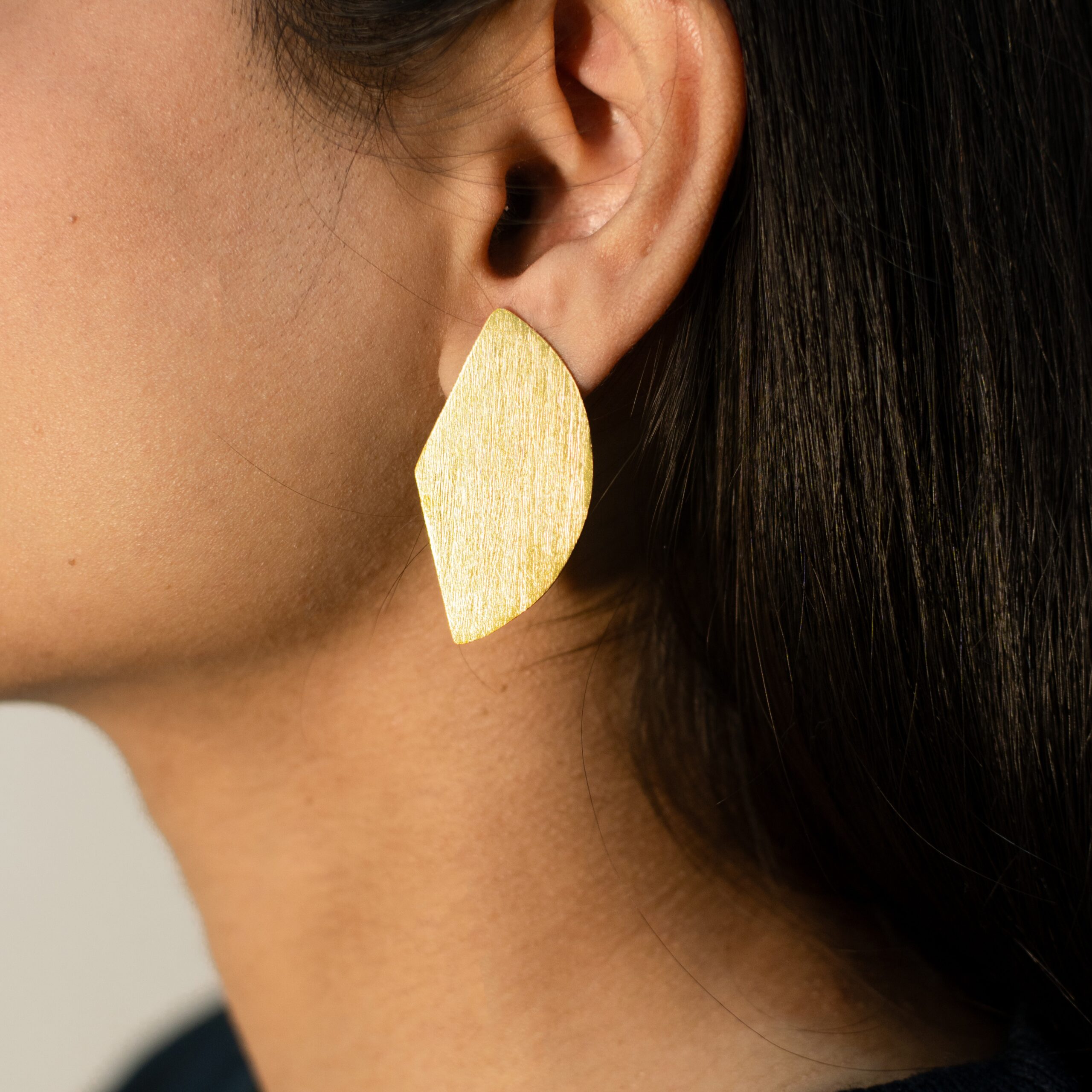 Left ear close-up: Masaira Split Circle gold-plated asymmetrical stud made from one split circle, brushed texture