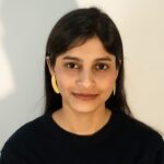 Front view: model wearing Masaira Split Circle asymmetrical gold-plated stud earrings made from one split circle, brushed texture