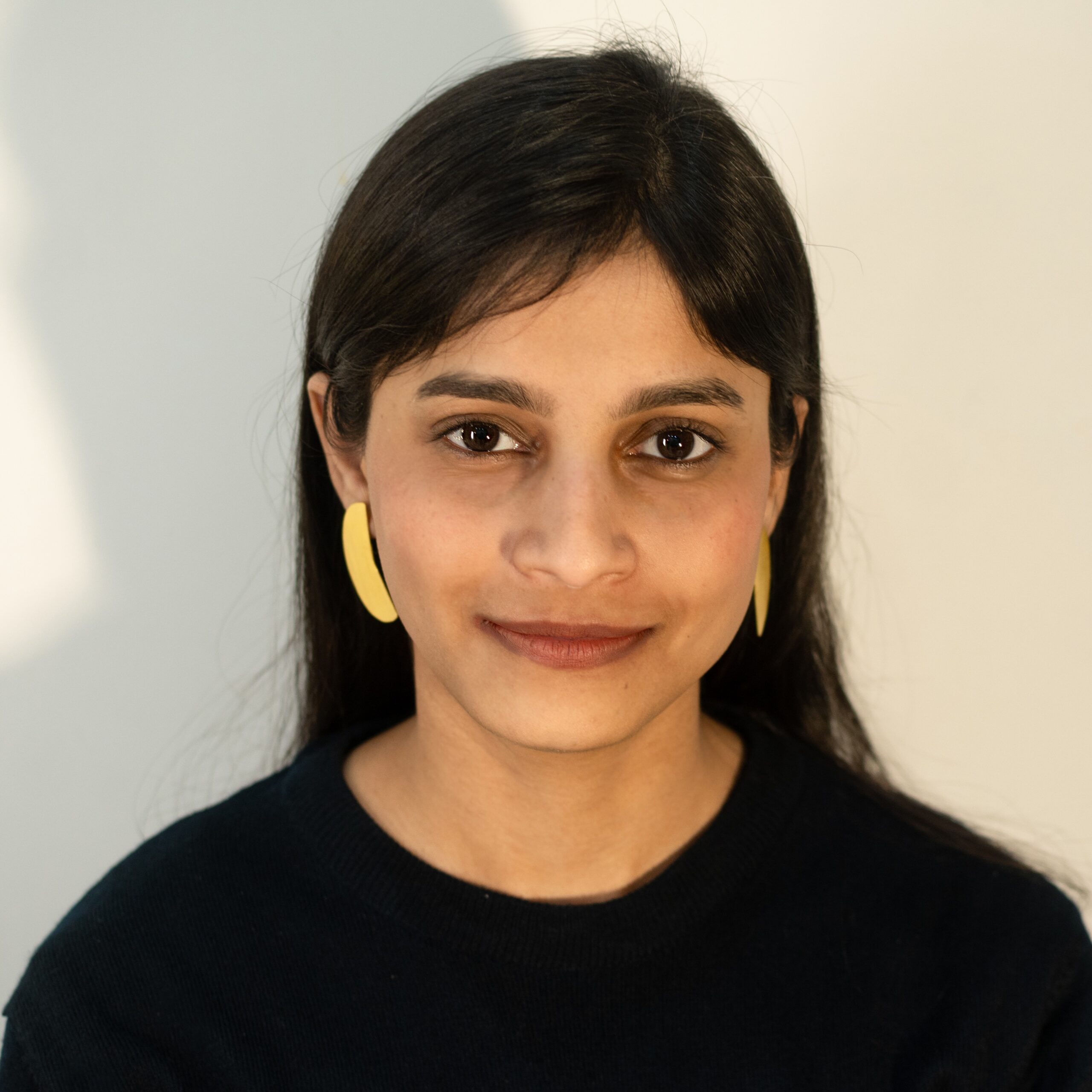Front view: model wearing Masaira Split Circle asymmetrical gold-plated stud earrings made from one split circle, brushed texture