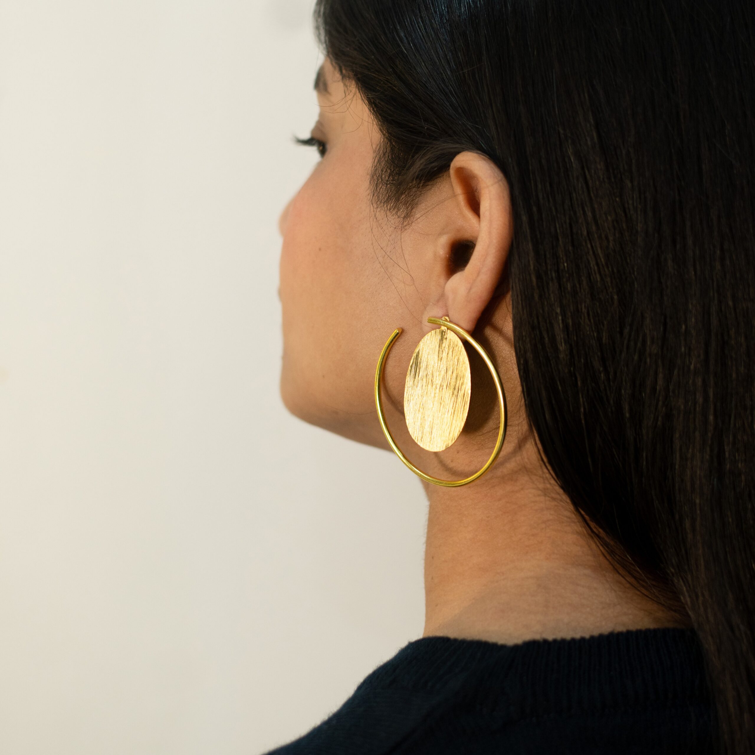 Right profile: model wearing Masaira Orbit gold-plated open-hoop earring with brushed oval disc