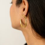 Rear three-quarter: model wearing Masaira Double Arc helix gold-plated double-band open hoop