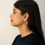 Left profile: Masaira Double Arc gold-plated double-band open-hoop earring on ear