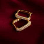Masaira Dazzle gold-plated rectangular huggie earrings with pavé stones, photographed on deep maroon satin fabric