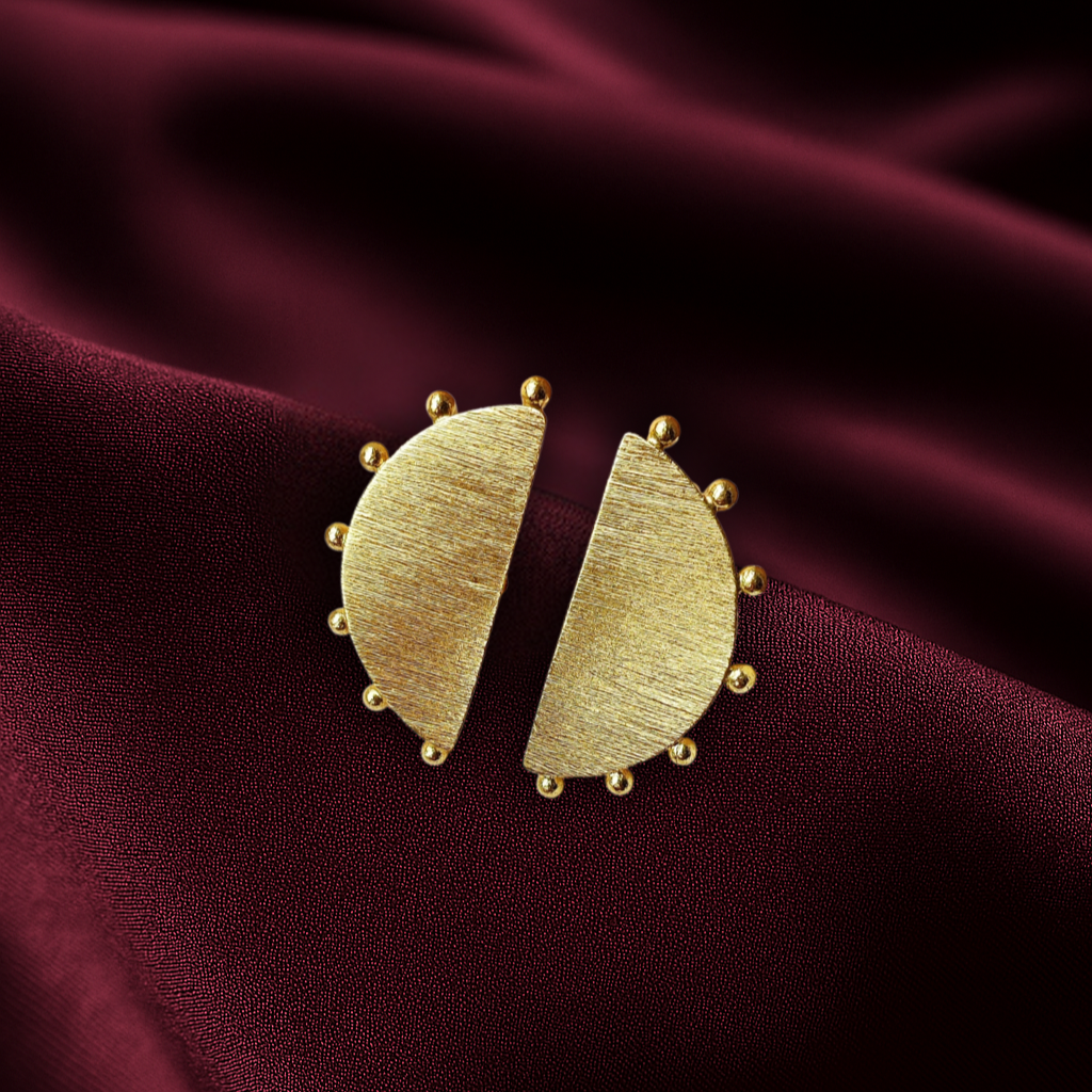 Masaira Eclipse Gold-Plated Half-Moon Beaded Edge Stud Earrings Masaira Eclipse gold-plated half-moon stud earrings with brushed texture and beaded edge on deep maroon satin