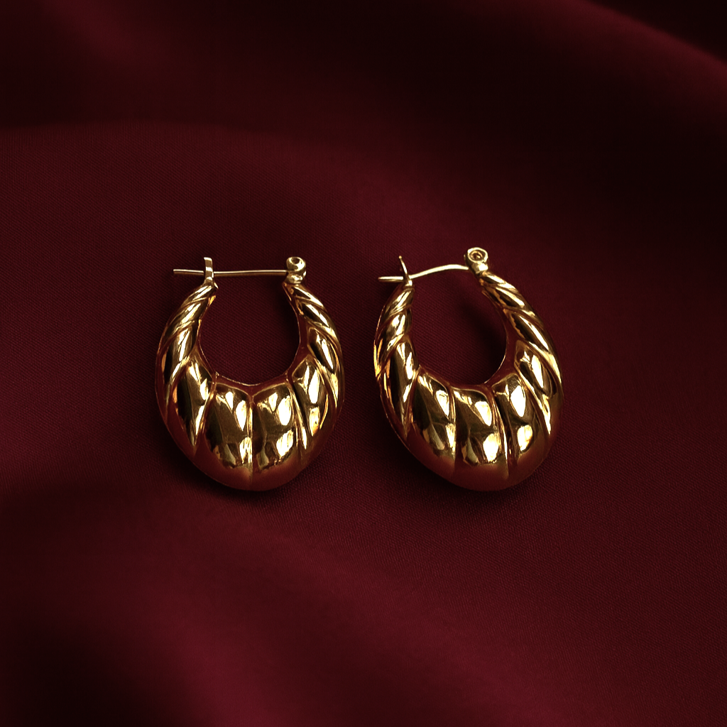 Minimalist triangular brushed gold-plated earrings on maroon satin fabric