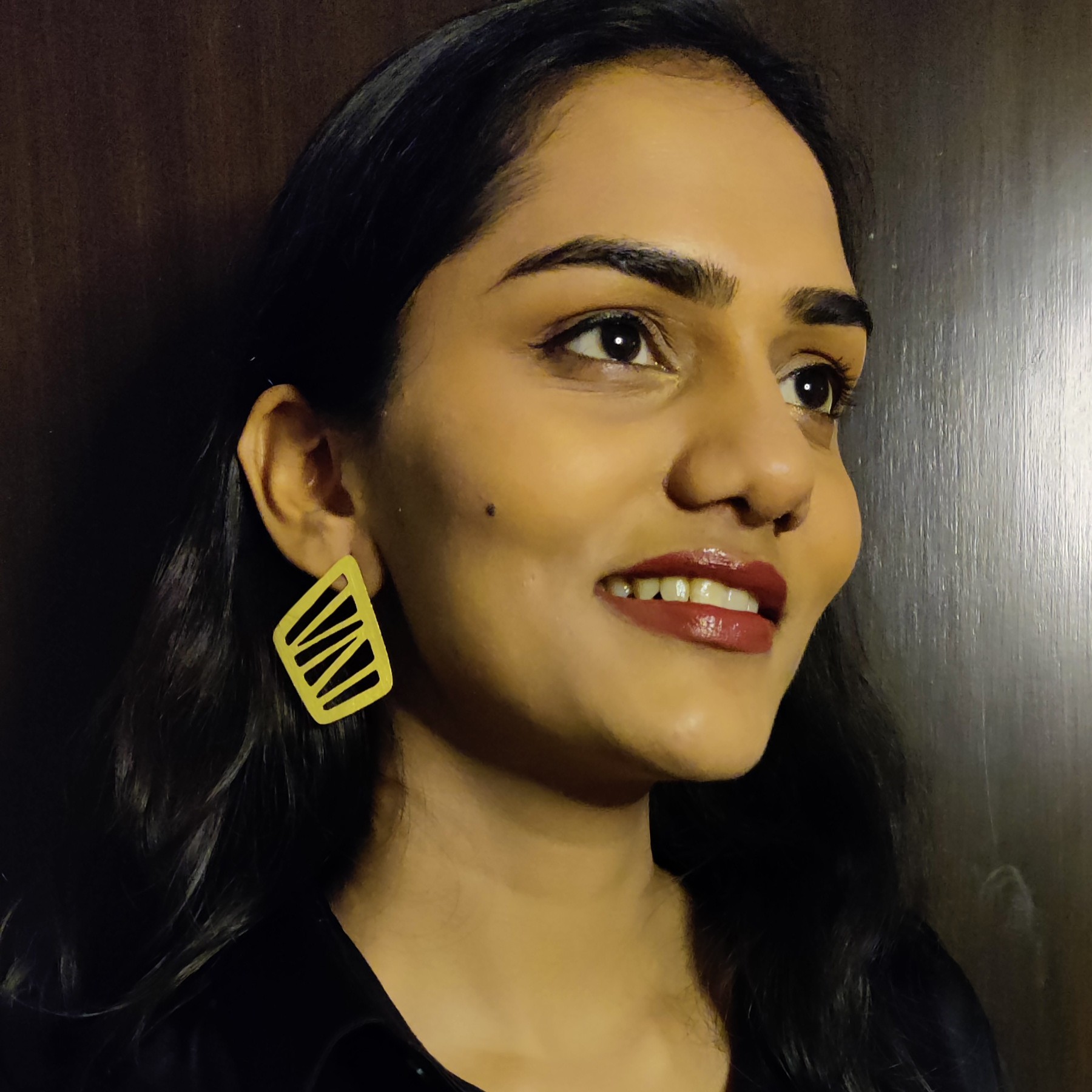 Modern Geometric Cut-Out Gold Statement Earrings – Lightweight & Bold Design Close-up of smiling woman showcasing statement cut-out earrings in matte gold finish, angled from the side.