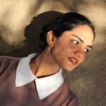 Minimalist gold-plated hoop earrings named Solace by Masaira, worn by a woman in natural sunlight, showcasing elegant everyday jewelry design.