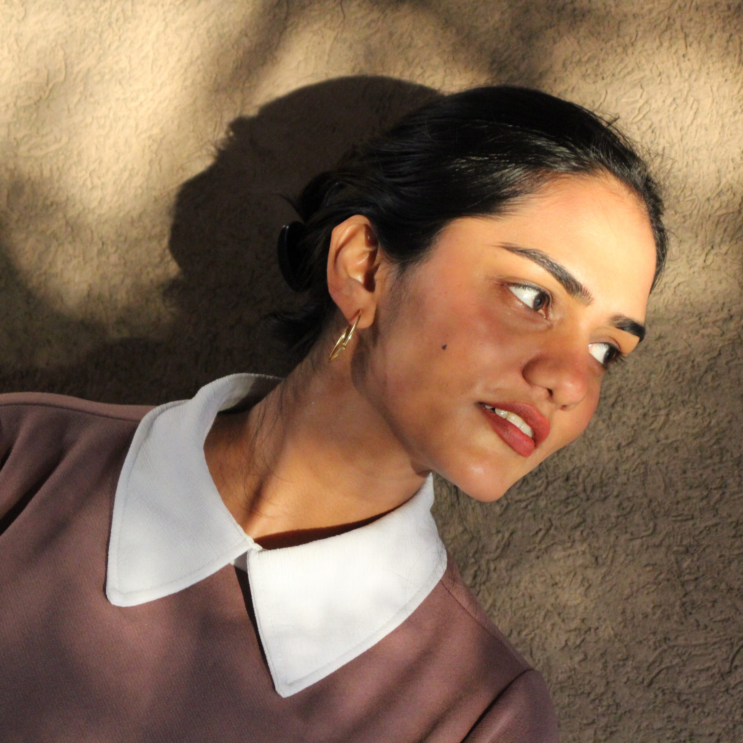 Minimalist gold-plated hoop earrings named Solace by Masaira, worn by a woman in natural sunlight, showcasing elegant everyday jewelry design.