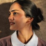 Alt Text: Woman wearing Masaira’s “Solace” gold-plated geometric hoop earrings, minimal modern design with intersecting lines, styled in natural light.