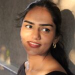 Portrait of model wearing Masaira Luna Drop gold teardrop huggies, classic everyday hoop size with high-polish glow.