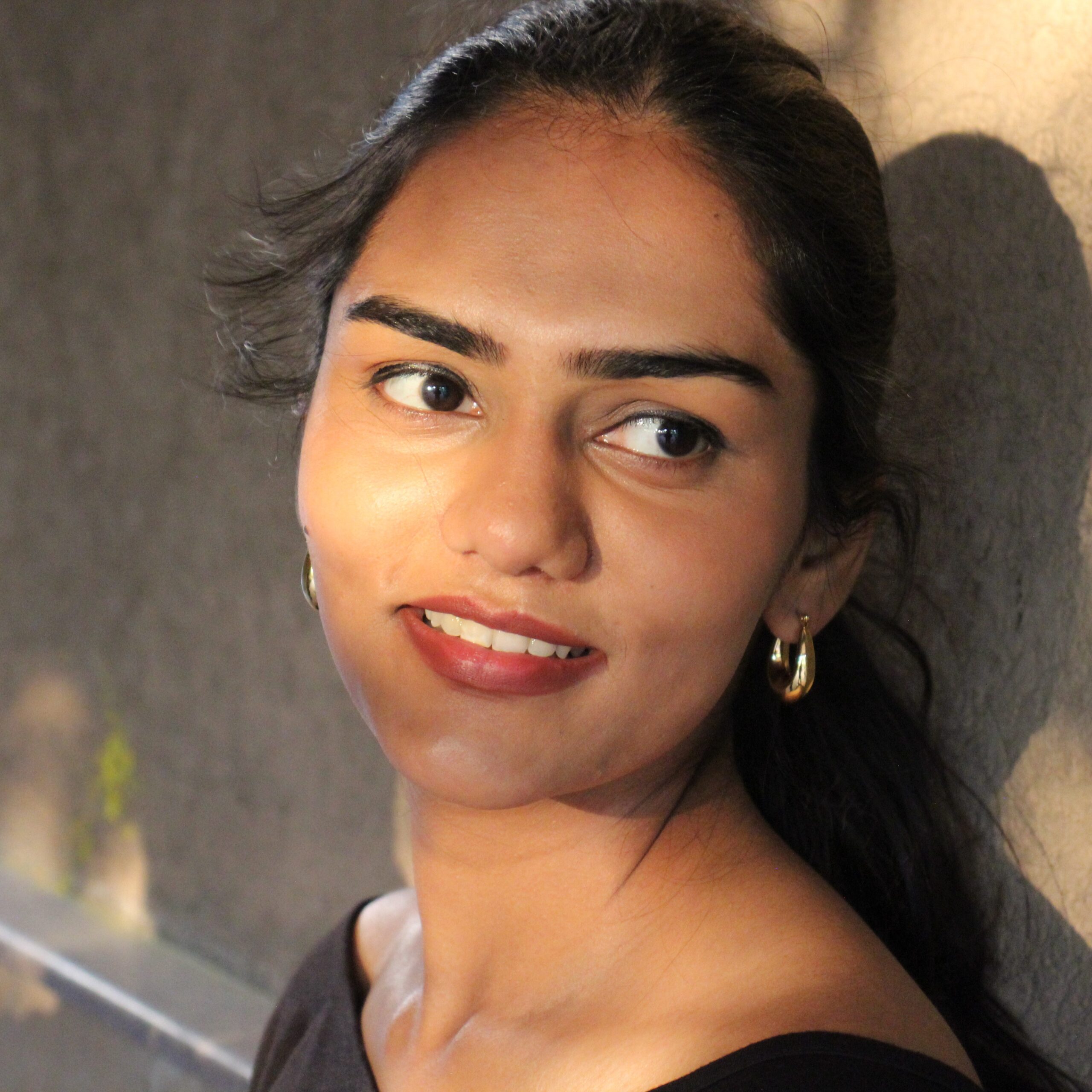 Portrait of model wearing Masaira Luna Drop gold teardrop huggies, classic everyday hoop size with high-polish glow.