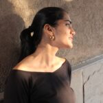 Close side view of Masaira Luna Drop gold-plated huggie hoops on ear, compact teardrop shape with hinged clasp.