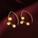 Masaira Myra gold-plated marquise open-frame earrings with three round coin discs on deep maroon satin