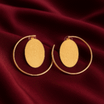 Gold-plated open-hoop earrings — Masaira Orbit — brushed oval disc on deep maroon satin