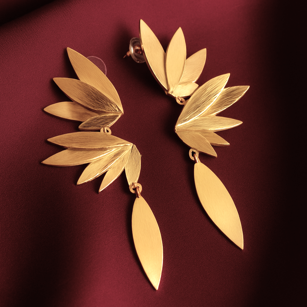 Phoenix gold-plated earrings with layered leaf design on maroon satin fabric