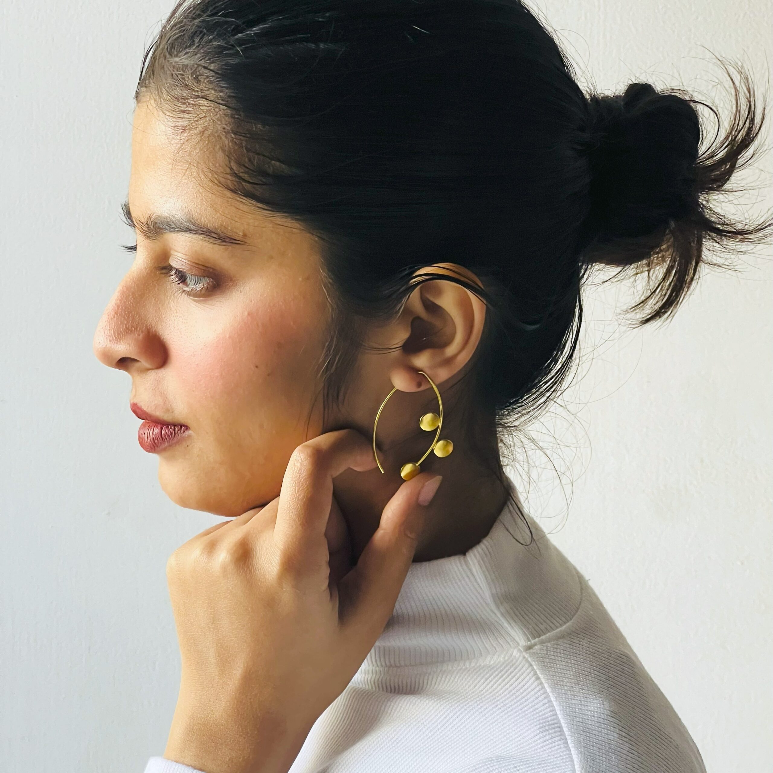 "Minimalist gold-plated hoop earring with dual sphere accents styled on model – modern contemporary jewelry by Masaira"