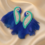 : Handcrafted blue parrot earrings with beaded detailing and bold feather tails on satin fabric