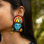 Close-up outdoor profile of model with straight hair wearing Krishna temple earrings in blue, red, yellow and gold beads — Masaira ethnic jewellery