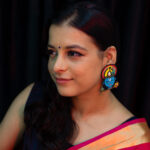 Model in pink saree smiling softly while wearing Krishna motif beaded earrings — Masaira deity-inspired jewellery