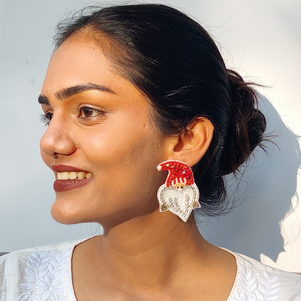 Profile shot of festive beaded Santa hat earring worn by model