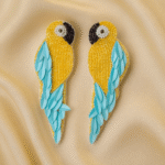 Teal-blue parrot-shaped beaded earrings with golden body and satin background