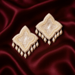 Pair of pearl and sequin beaded statement earrings placed on rich maroon satin fabric.