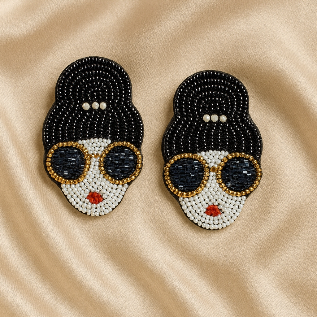 Glam Girl Beaded Earrings – Bold & Stylish Statement Jewelry Beaded earrings shaped like a stylish woman’s face with black hair, pearl details, gold-rimmed sunglasses, and red lips on a champagne satin background.