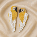 "Handcrafted yellow beaded parrot earrings with white wing detail worn by a model in a lime green dress"