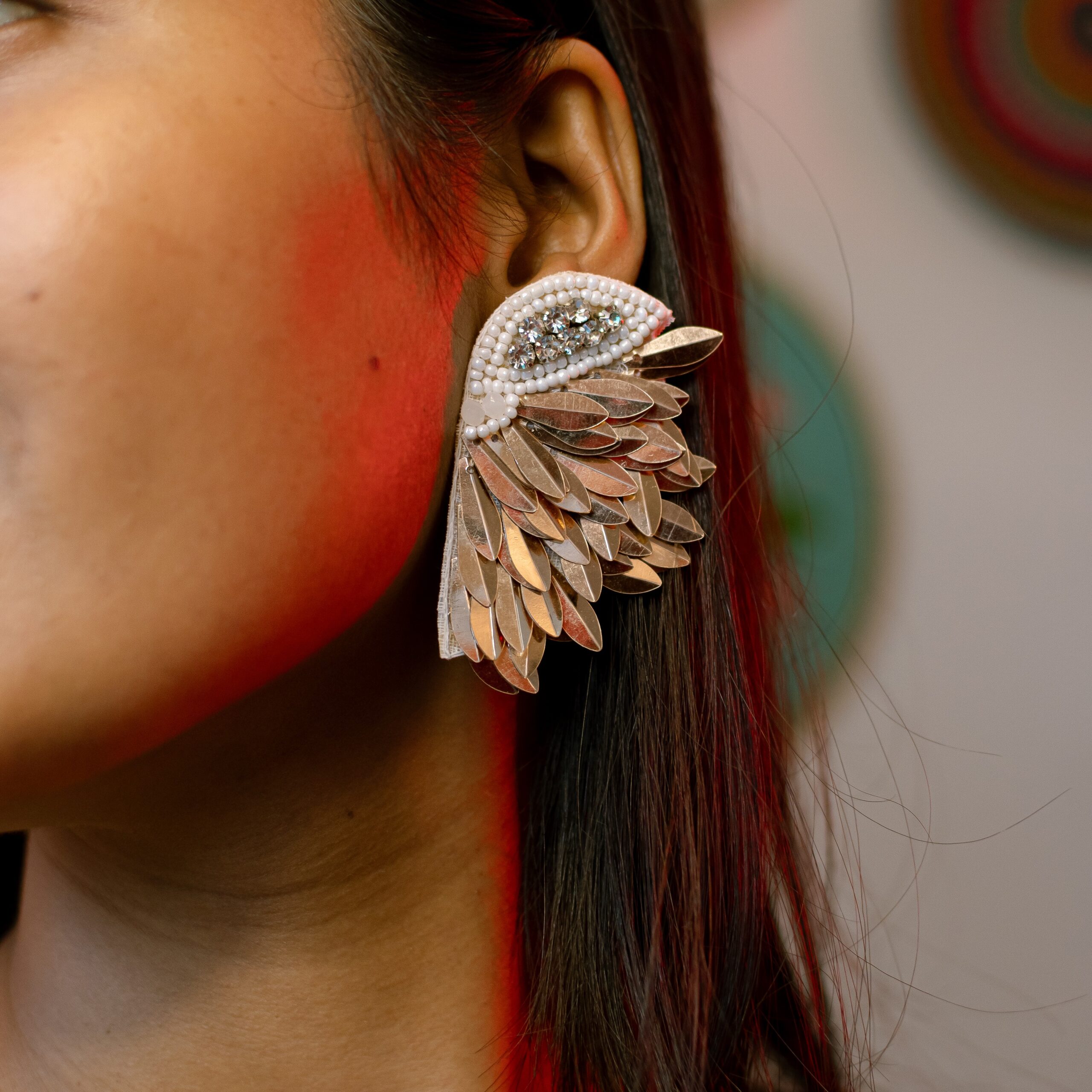 Woman wearing Masaira’s Celestial Wings beaded earring in a silver feathered design