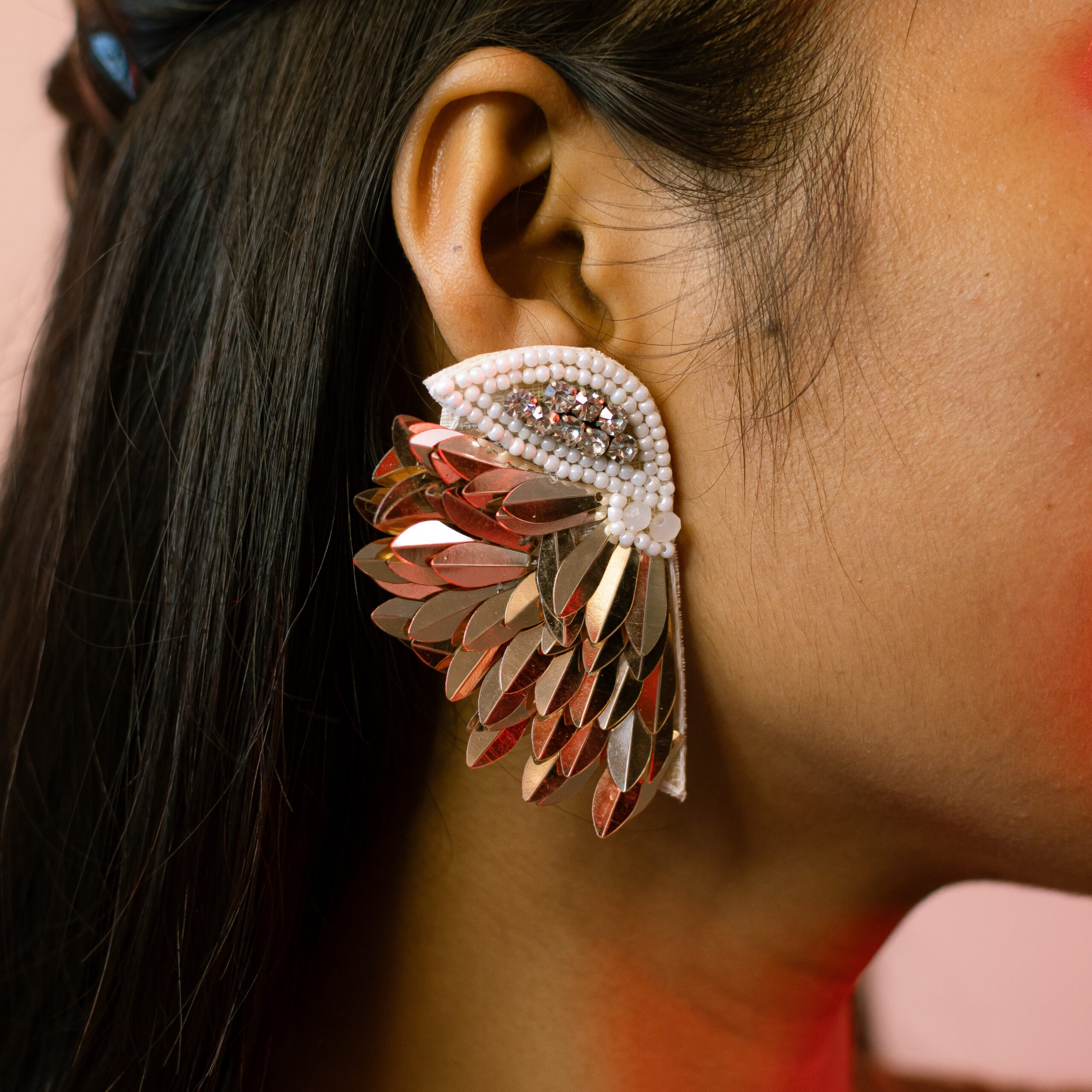 Extreme close-up of Masaira's Celestial Wings earring featuring layered silver beads and wing-inspired design details.