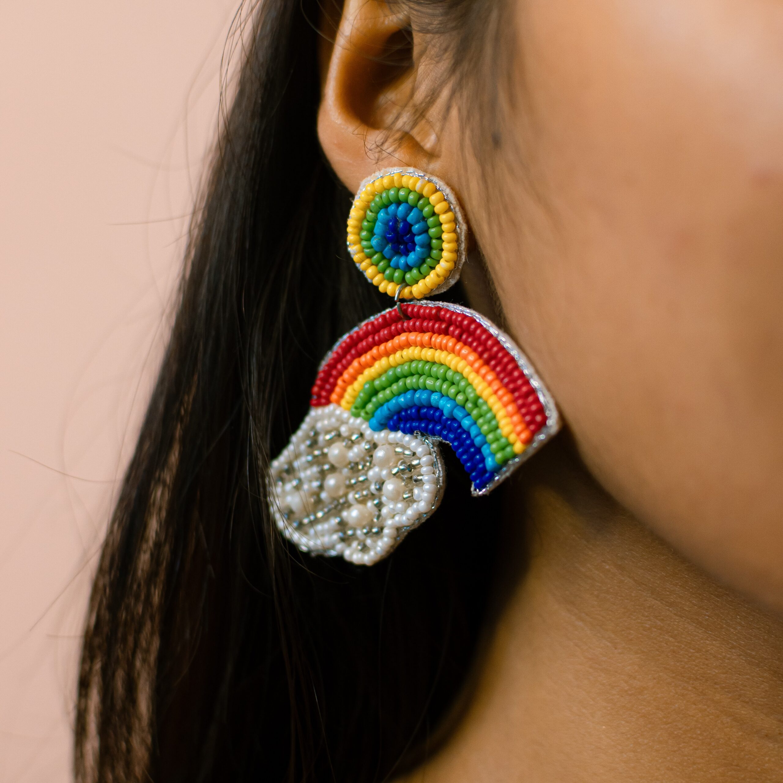 Detailed close-up of rainbow beaded earrings with pearl cloud design