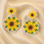 Pair of handcrafted sunflower beaded earrings placed on a luxurious champagne satin fabric.