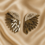 Masaira Celestial Wings earrings displayed on champagne satin fabric background
