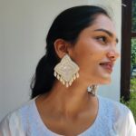 Model wearing handcrafted ivory beaded earrings with pearl droplet detailing, styled with a white embroidered kurta.