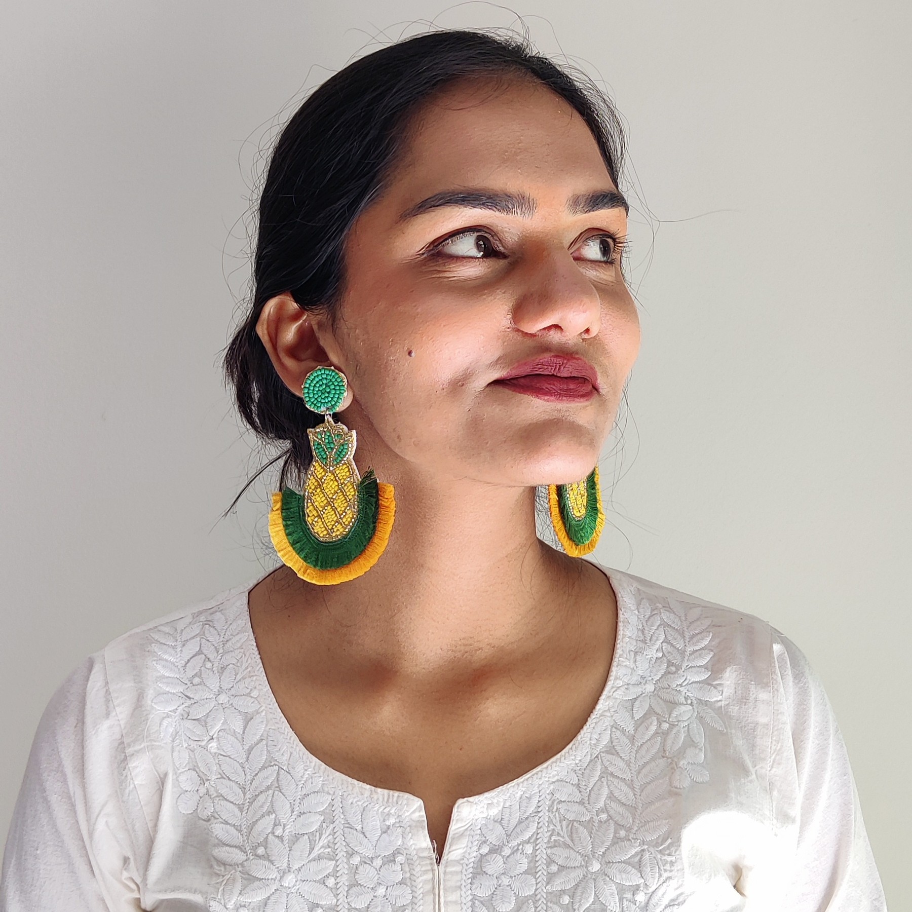 Tropical Radiance – Pineapple Earrings by Masaira Close-up of Indian woman wearing Masaira's yellow-green pineapple beaded earrings with white kurta.