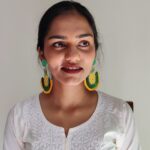 Indian woman wearing handcrafted pineapple beaded earrings from Masaira, dressed in white kurta, smiling naturally.