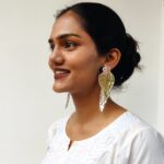 Model looking left and smiling while wearing long gold parrot earrings — Masaira statement jewellery