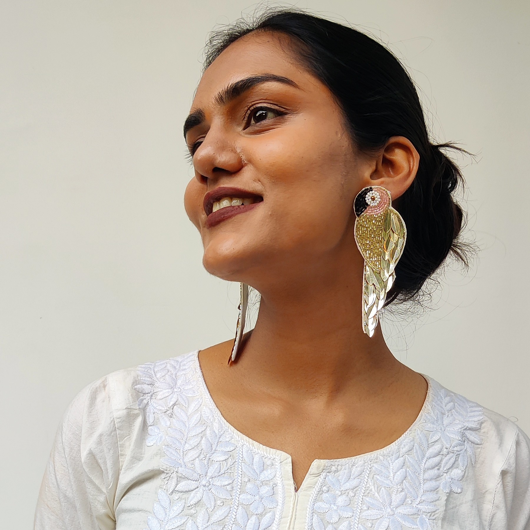 Gold Parrot Earrings – Upward Gaze Editorial Frame | Masaira Model looking upward while wearing designer gold parrot earrings — handcrafted Masaira jewellery in white ethnic kurta