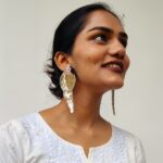 Model looking upward while wearing designer gold parrot earrings — handcrafted Masaira jewellery in white ethnic kurt