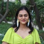 "Handcrafted yellow beaded parrot earrings with white wing detail worn by a model in a lime green dress"