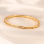 Slim gold-plated bangle with white cubic zirconia stones from Masaira on a satin background