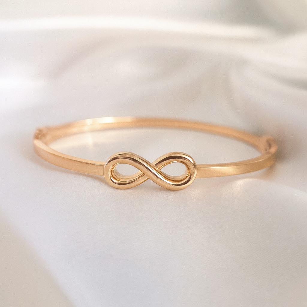 Infinity Embrace Bangle – 18K Gold-Plated Symbol Bracelet by Masaira Gold-plated infinity symbol bangle bracelet on soft white satin background by Masaira