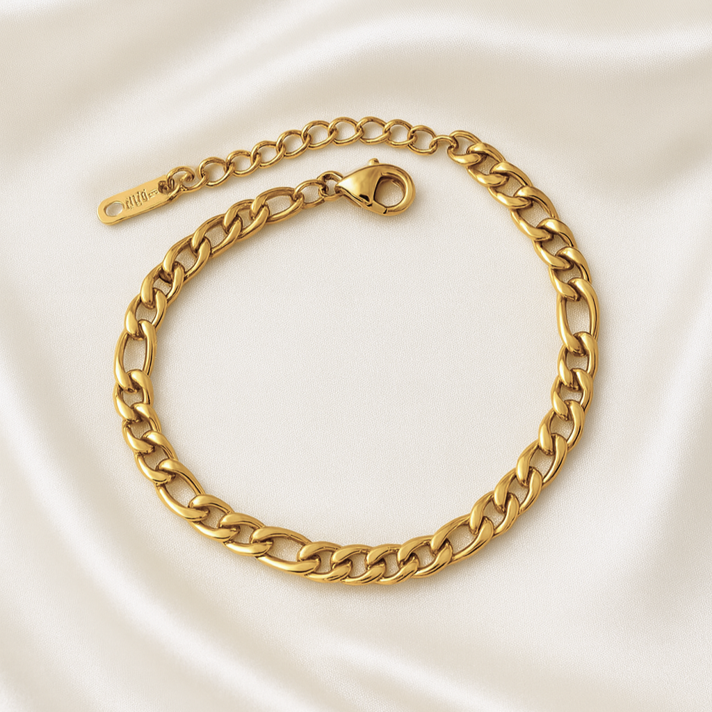 Gold Cuban link chain bracelet with adjustable clasp on ivory satin background